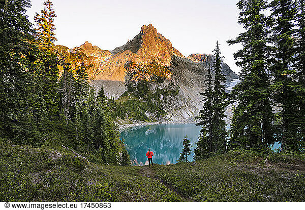 Female In Red Jacket Next To Gorgeous Turquoise Alpine Lake At Sunset