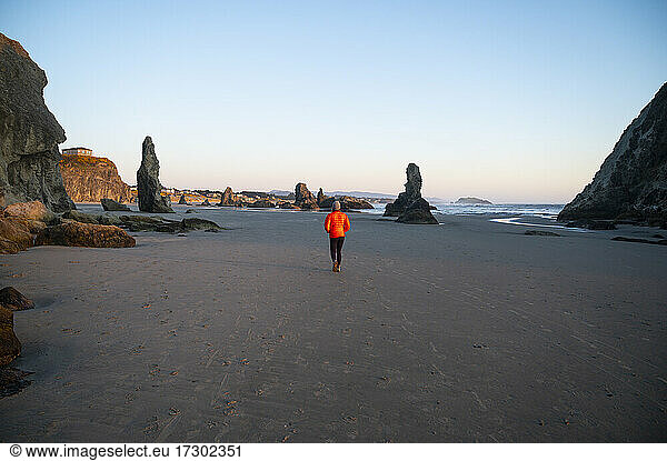 Female In Red Puffy Jacket Walking On The Beach At Low Tide