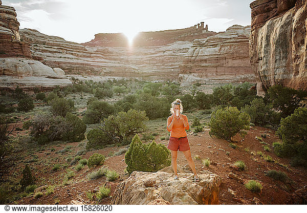 female in workout clothes takes picture with cellphone in desert light