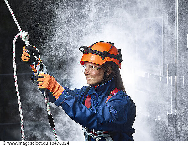 Female industry worker attaching carbiner to climbing rope