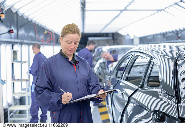 Female inspector in paint shop in car factory