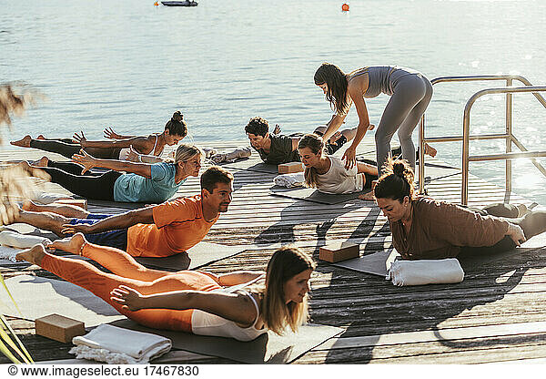Female instructor guiding woman doing yoga during class