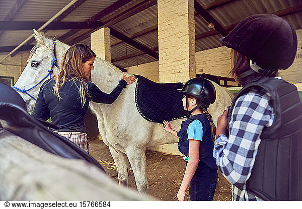 Female instructor helping girls prepare for horseback riding