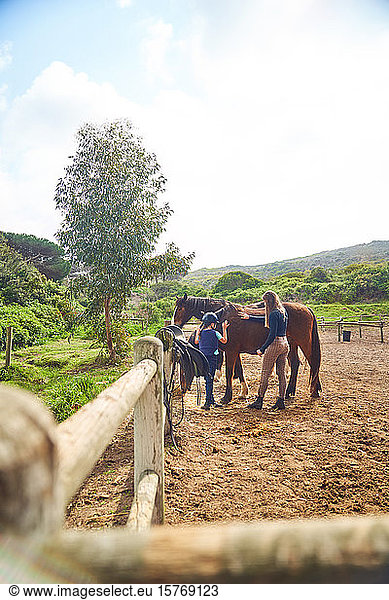 Female instructor teaching horseback riding to girl in sunny paddock