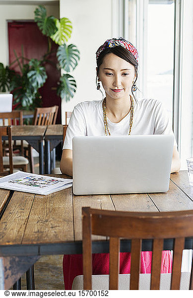Female Japanese professional sitting at a table in a co-working space  using laptop computer.