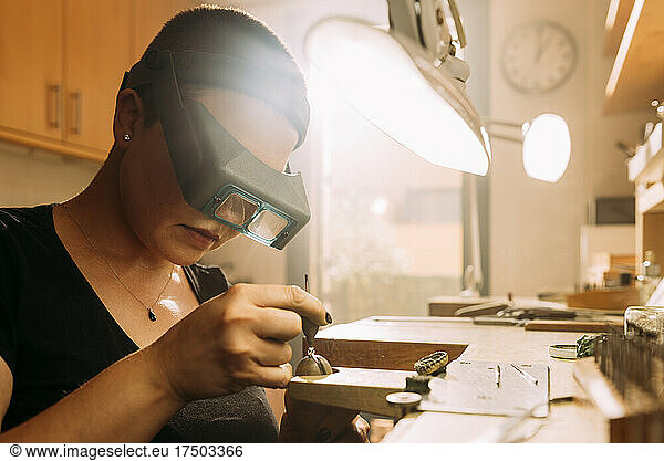 Female jeweler positioning diamond in ring at workshop