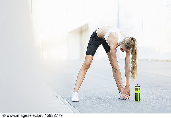 Female jogger stretching her legs in the city