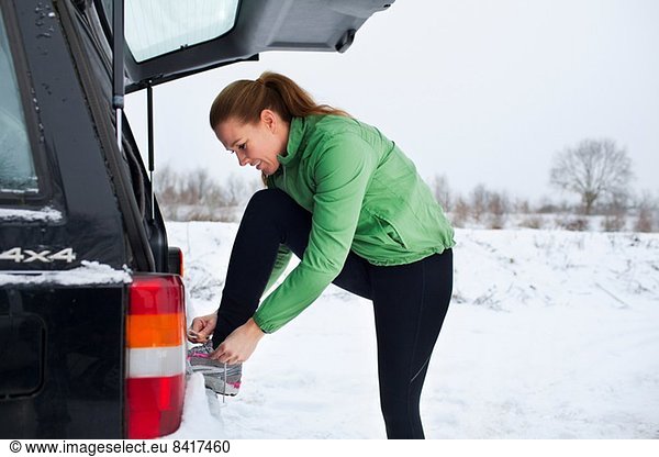 Female jogger tying shoelaces in snow covered scene