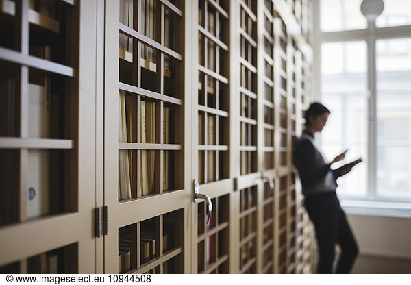 Female lawyer leaning on bookshelf in library