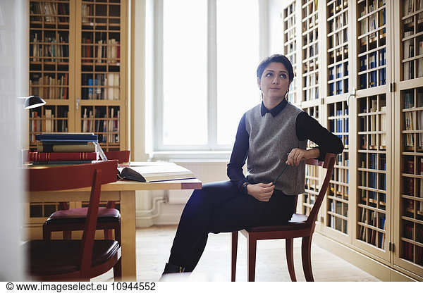 Female lawyer looking up while sitting in library