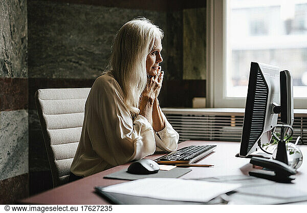 Female lawyer with long white hair staring at computer in office
