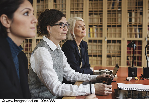 Female lawyers listening in meeting while sitting at table