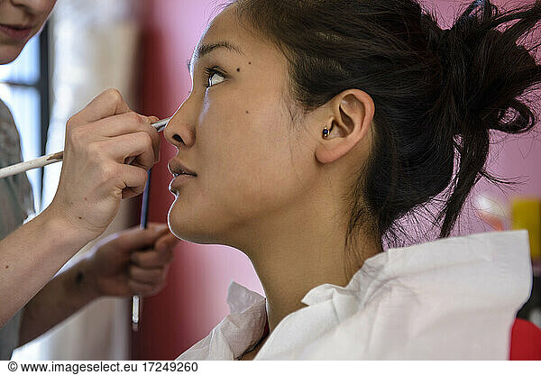 Female make-up artist applying make-up on model in studio