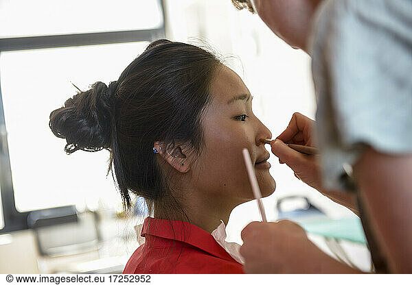Female make-up artist applying makeup on model in studio