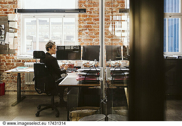 Female manager using laptop while sitting at desk in creative office
