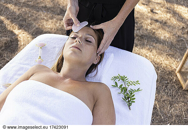 Female massage therapist massaging customer with gemstone