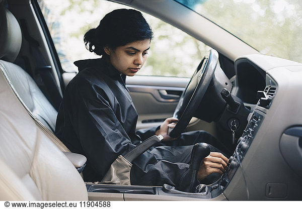 Female mechanic adjusting knob on dashboard in car