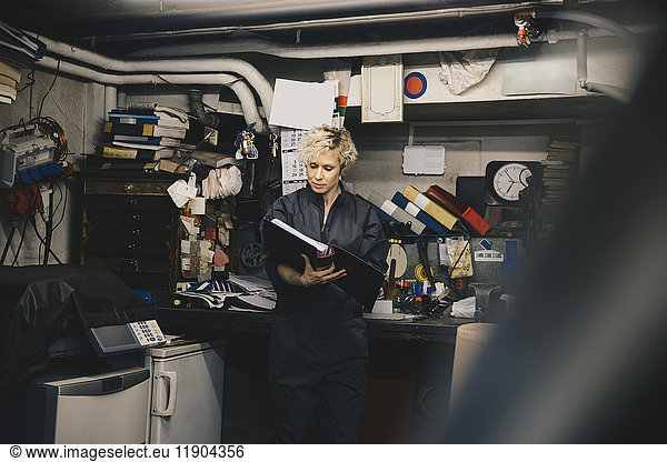 Female mechanic reading document in auto repair shop