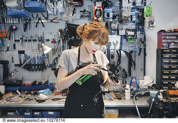 Female mechanic repairing pedal in workshop