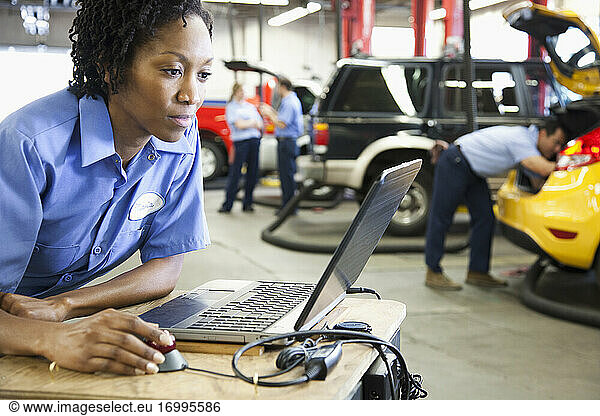 Female mechanic using a laptop  diagnostic electronics  in an auto repair shop