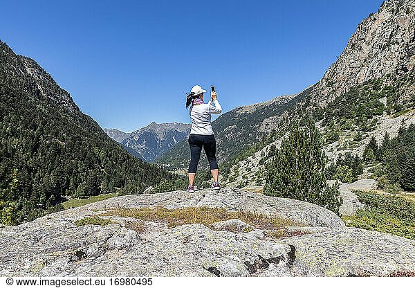 Female middle aged tourist take pictures with mobile phone in Spanish Pyrenees mountain in a sunny day