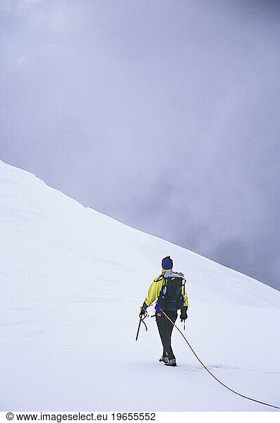 Female mountaineer climbing a glacier.