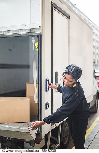 Female mover opening door of truck on street in city