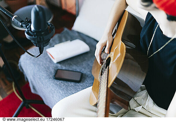 Female musician playing guitar in studio