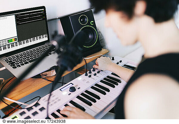 Female musician playing piano while composing in studio
