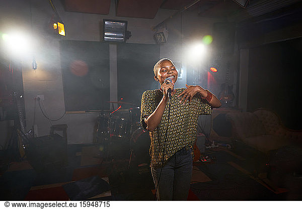 Female musician singing into microphone in recording studio