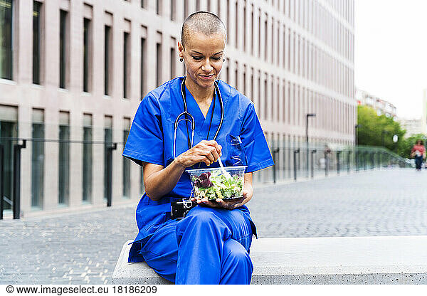 Female nurse having salad on bench