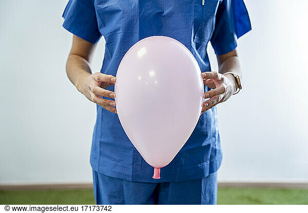 Female nurse holding pink balloon