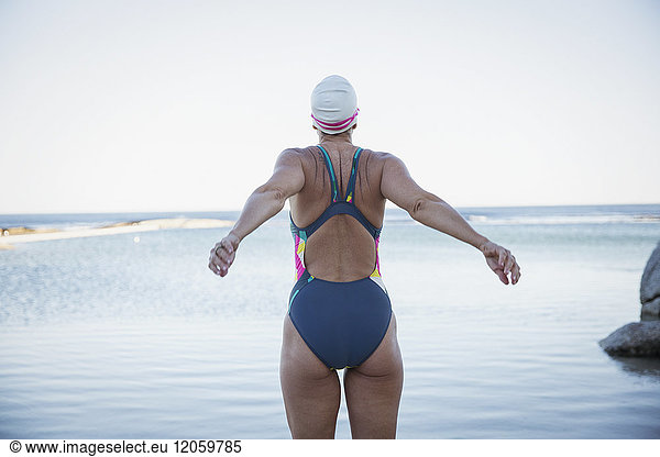 Female open water swimmer stretching at ocean