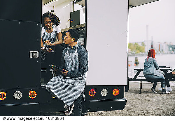 Female owner and assistant discussing in food truck