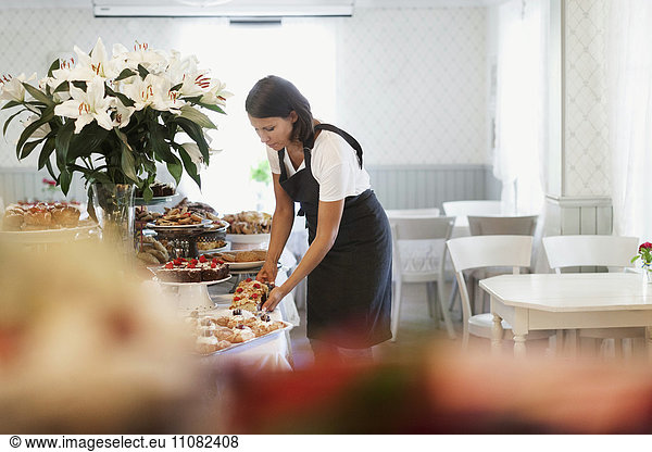 Female owner arranging desserts on table at cafe