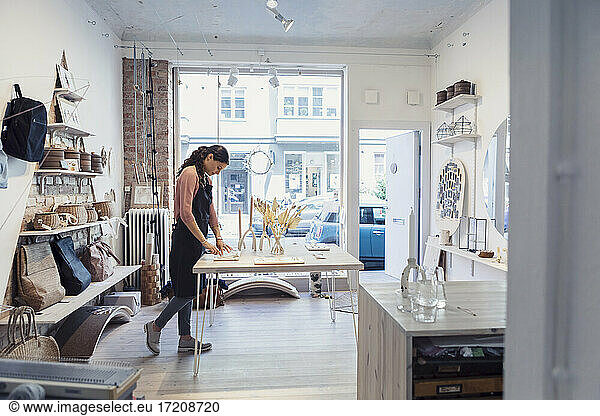 Female owner examining jewelry while standing in design studio