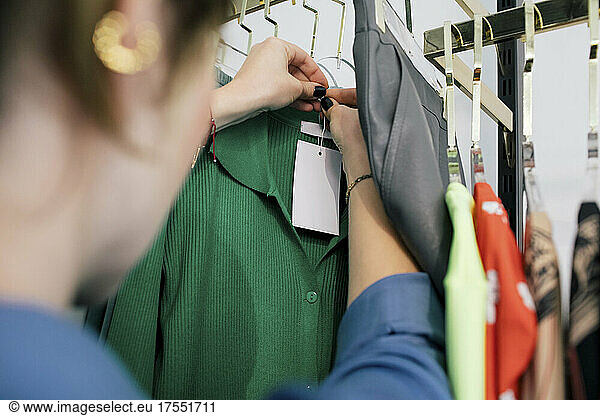 Female owner tying price tag on clothes in store