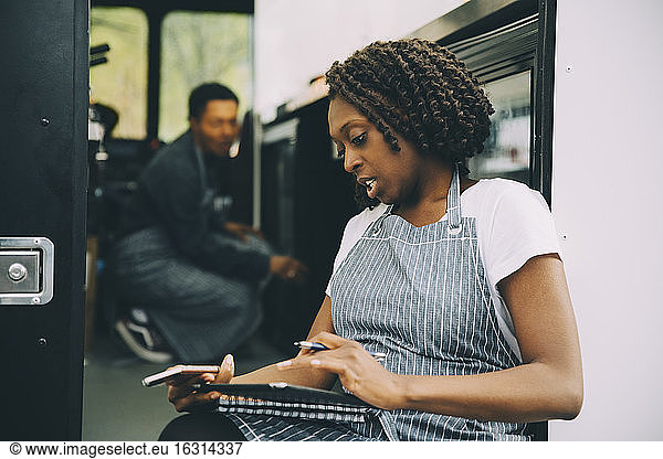 Female owner using digital tablet against food truck
