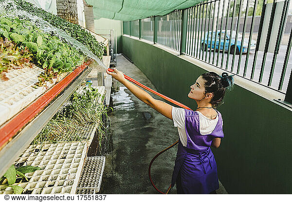 Female owner watering plants at nursery