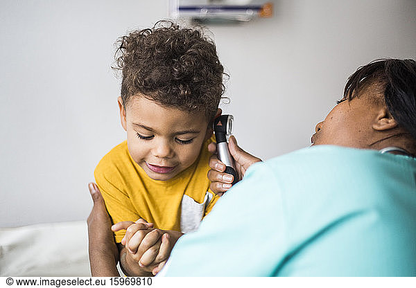 Female pediatrician examining boy's ear in medical clinic