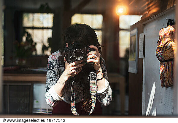female photographer takes self portrait in mirror at home