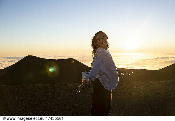 female poses for photo at sunset on top of Mauna Kea