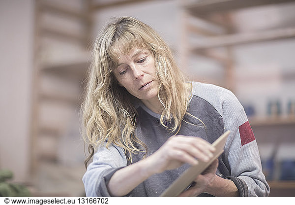 Female potter touching edge of plate in workshop