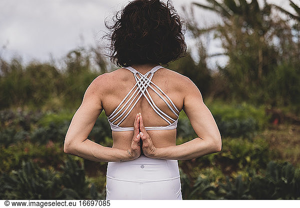 Female practices yoga outside in a field in hawaii