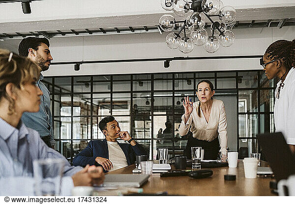 Female professional gesturing while explaining colleagues in board room
