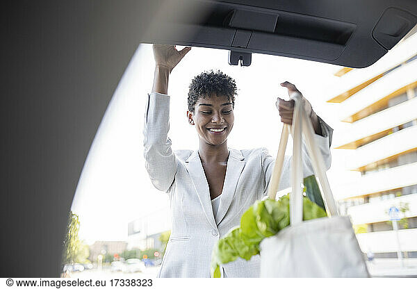 Female professional loading groceries in car trunk