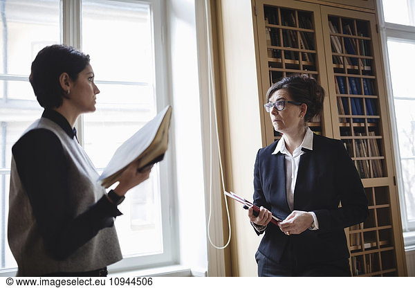 Female professionals discussing with lawyer in library