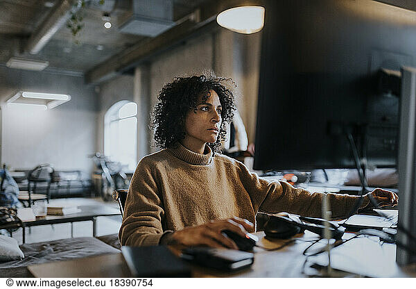Female programmer concentrating while working on computer at desk in office