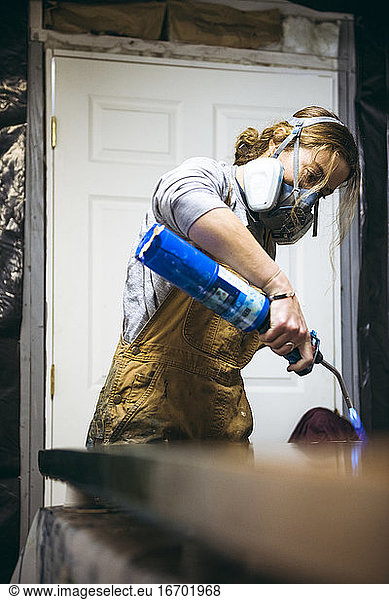 Female resin artist using blowtorch to finish artwork