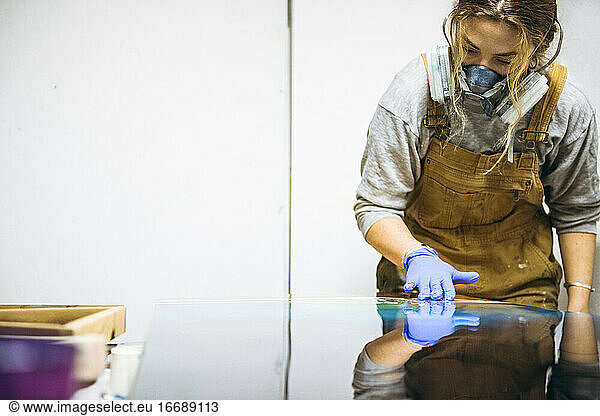 Female resin artist using hands to perfect artwork